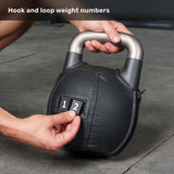 A person attaches numbered Kettlebell Wrap labels from Bells of Steel USA to a black adjustable kettlebell with a silver handle. The text at the top reads, “Hook and loop weight numbers.”.