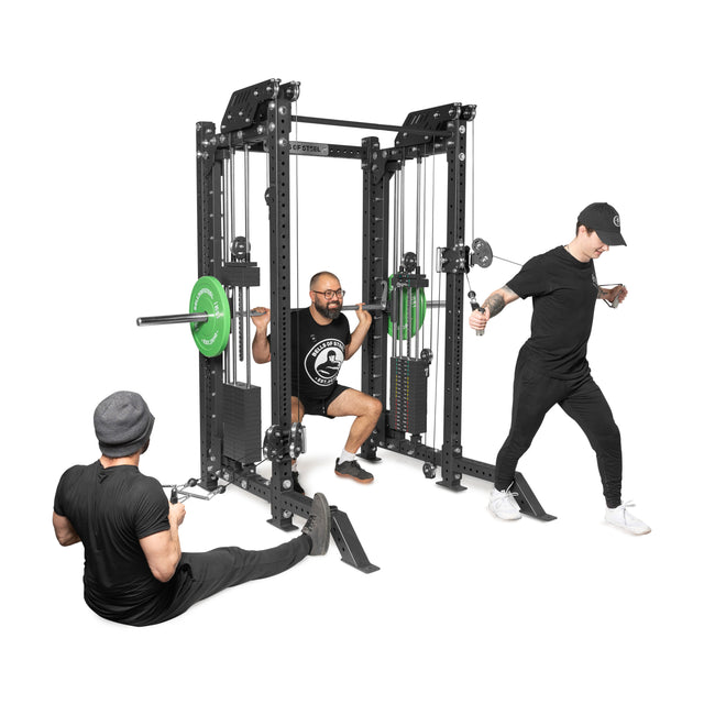 Three individuals use THE KOLOSSOS - Smith Functional Trainer by Bells of Steel. One squats with a barbell on the Smith Machine, another sits on the floor with a phone, and the third performs a cable exercise—all dressed in black athletic wear.