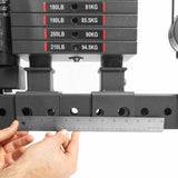 Close-up of an individual measuring ground clearance beneath a weight stack on THE KOLOSSOS - Smith Functional Trainer by Bells of Steel. A metal ruler ensures precision as sleek black plates, labeled in pounds and kilograms, are clearly visible.