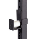 Close-up of the Bells of Steel Light Commercial Power Rack (2.3" x 2.3", ⅝" holes) in black metal, featuring a white cylindrical barbell holder and secure J-cup attachment—perfect for home training versatility and barbell protection.