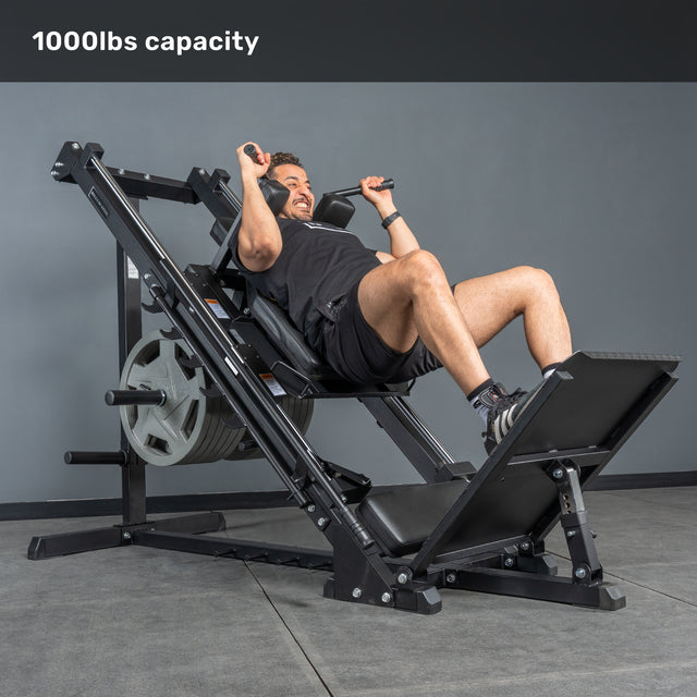 A man uses the Bells of Steel Leg Press Hack Squat Machine, loaded with weight plates, in a gym. Text at the top reads "1000lbs capacity.