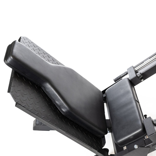 A black Bells of Steel Leg Press Hack Squat Machine with a padded seat and backrest stands against a white background. Ideal for home gyms, it features angled supports and a textured footplate for versatile exercises like hack squats.