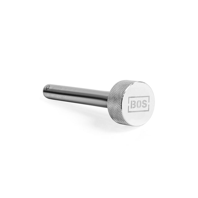 A sleek metal tool branded "BOS," featuring a cylindrical handle with a smooth finish and a textured grip similar to mag pins, is elegantly angled against a white backdrop. This tool is known as the Magnetic Rack Attachment Pins by Bells of Steel.