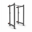 The Manticore Folding Power Rack - Prebuilt by Bells of Steel features black 3"x3" uprights, 1" holes, and red safety pins for weightlifting and strength training in a home gym, shown against a white background.