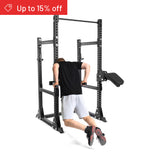 A person in a black shirt and gray shorts does dips on the Bells of Steel Manticore Half Rack Builder (3" x 3", 1" Holes). A red banner in the top left reads "Up to 15% off." Perfect for any home gym.