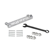 A metal bar labeled with "Bells of Steel" sits beside a combination wrench, with silver screws and nuts neatly organized as part of the Manticore Hardware kit.