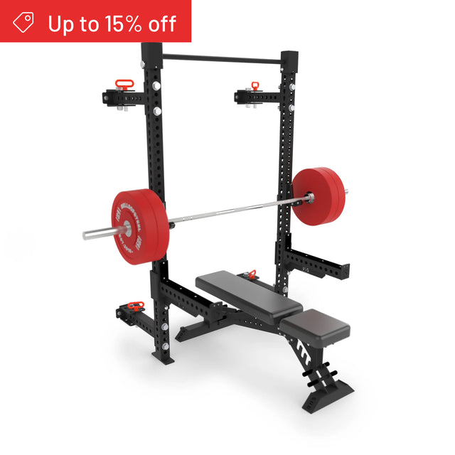 A black adjustable weight bench with a loaded barbell and red plates rests on the Bells of Steel Manticore Folding Half Rack Builder (3" x 3", 1" Holes). A red banner at the top left reads “Up to 15% off.”.