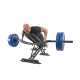 A man grips the Bells of Steel Omni Bar, intensely performing rows on a T-bar row machine. The blue plates contrast his black shirt and white shoes, with the equipment set against a plain white background, exemplifying sleek power and focus.