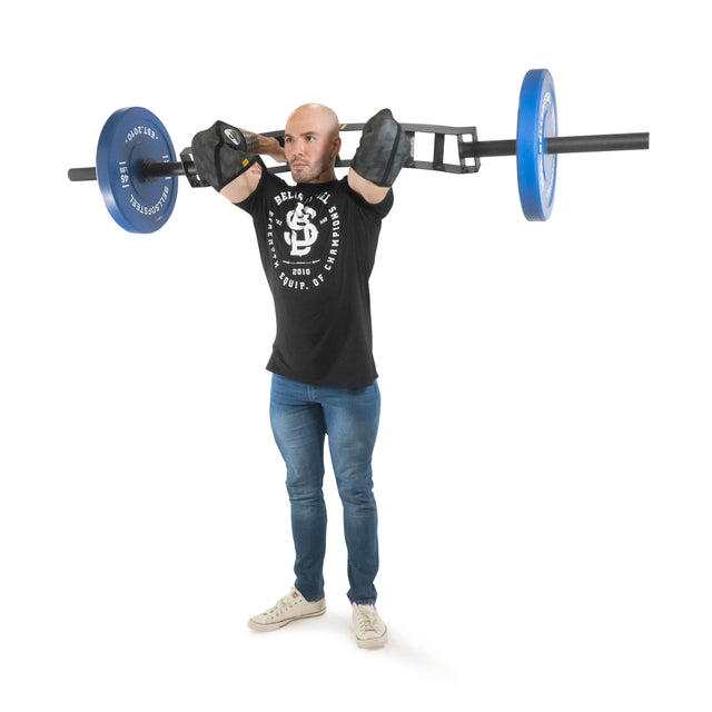 A person lifts the Omni Bar by Bells of Steel, featuring blue weights and precise knurling for a secure grip. Dressed in a black shirt, jeans, and white sneakers, they focus intensely on the exercise against a white background.