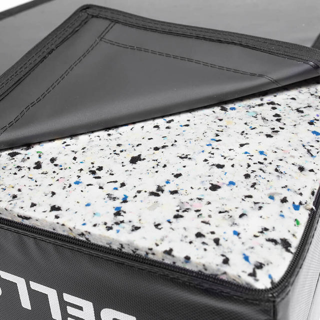 Close-up of a folded Bells of Steel Deadlift Pad, showcasing foam fillers with a speckled pattern of white, black, and blue dots in the inner layer. The black outer layer is partially open, revealing the vibrant pattern beneath.