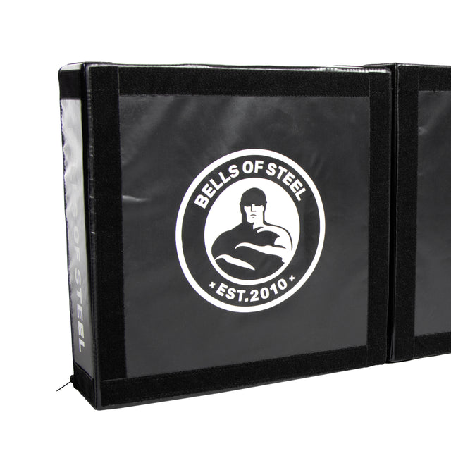 The Bells of Steel Deadlift Platform Drop Pad Pair is a black crash mat featuring the "Bells of Steel Est. 2010" logo and a white muscular figure, designed to absorb impact and reduce noise during heavy lifts.