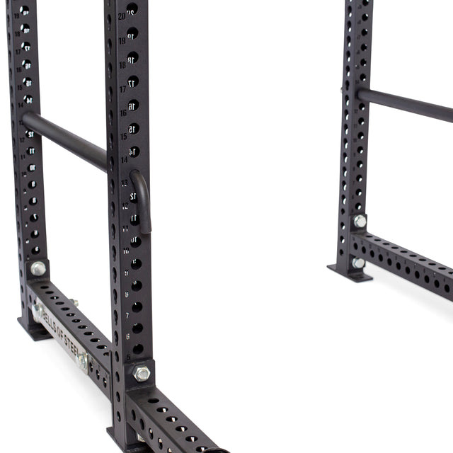 A partial close-up of Bells of Steel Pin Pipe Safeties showcases a black metal power rack with numbered holes and bolts. Its sturdy construction and versatility make it an ideal fit for fitness or weightlifting exercises.