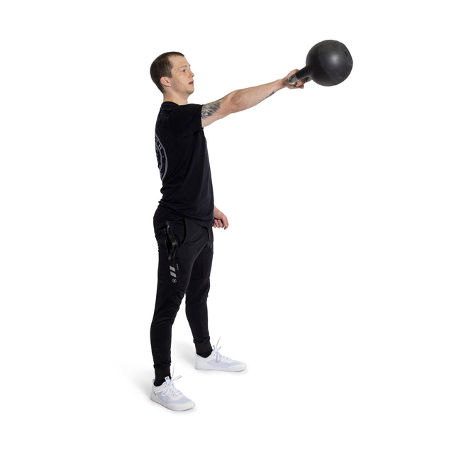 A man in a black t-shirt and pants executes a single-arm swing with a Bells of Steel adjustable kettlebell, extending it forward. He stands against a white background, sporting white athletic shoes.