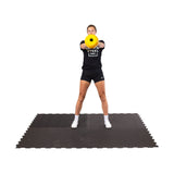 female athlete doing kettlebell swings on the Black Puzzle Mat