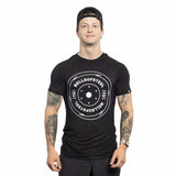 A person in a black Bells of Steel Bamboo T-Shirt and a backward cap stands facing forward, displaying tattooed arms, against a white background.