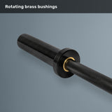 A close-up of the Bells of Steel Short Rackable Barbell in black shows its textured grip and a brass bushing near the sleeve against a gray background. The text above reads, “Rotating brass bushings.” Ideal for a compact home gym, this 69-inch barbell delivers both performance and space-saving versatility.