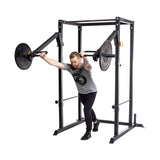 A man in athletic wear performs a chest press with a plate-loaded lever arm on the Bells of Steel Residential Power Rack (2.3" x 2.3", ⅝" holes), leaning forward and pushing the handles away from his chest—perfect for home gyms.