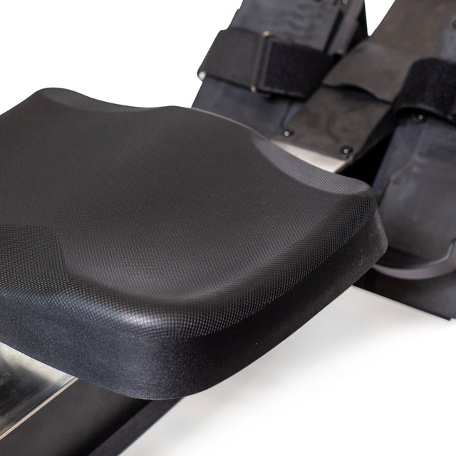 Close-up of a Blitz Air Rower by Bells of Steel, showcasing a black contoured seat with textured surface. Adjustable foot straps ensure secure positioning, ideal for low-impact cardio workouts.