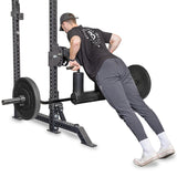 A man in athletic wear performs an inverted row on a squat rack using the versatile Safety Squat Bar - The SS4 by Bells of Steel, which features an ergonomic pad. He grips the bar with both hands, maintaining a horizontal angle to efficiently execute the exercise.