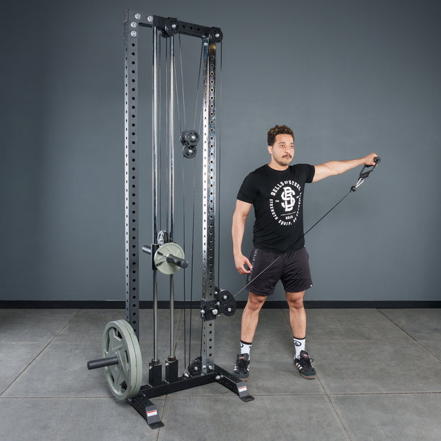 A man in a black t-shirt and shorts uses the Bells of Steel Fat Bar - Single D Handle on a cable machine, performing a lateral raise in the gym to improve grip strength.