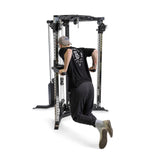 Wearing a cap and black workout attire, an individual demonstrates tricep dips on the Bells of Steel All-in-One Trainer, utilizing its versatile setup for effective resistance training.