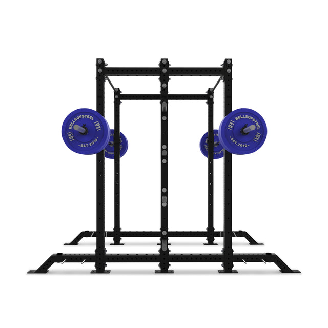 The Bells of Steel Hydra 2-Sided Rack is a sturdy black metal power rack with two blue barbells, featuring a rectangular frame and multiple adjustment holes—ideal for modular home gyms and strength training.