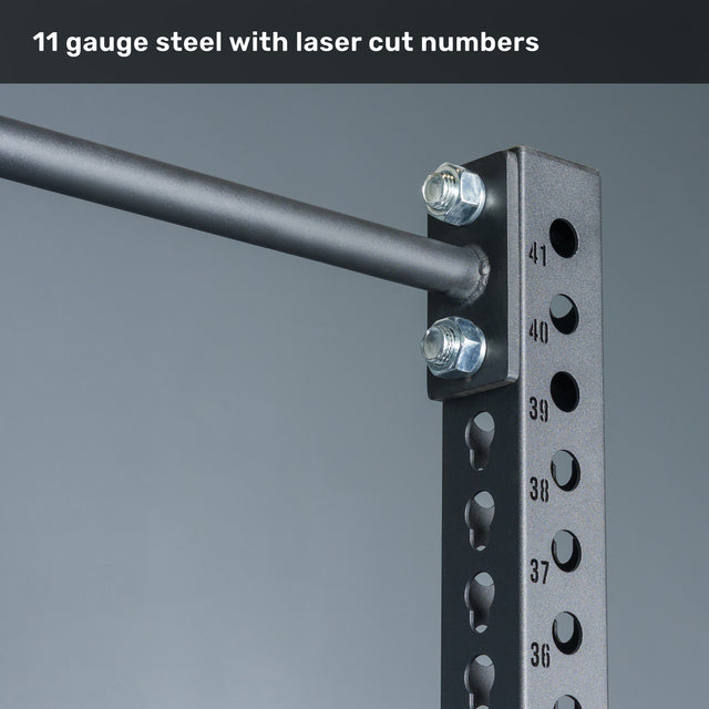 Close-up of the Bells of Steel Manticore Squat Stand - Prebuilt, featuring heavy-duty black 3" x 3" uprights, precise laser-cut 1" numbered holes, and secure bolts connecting a horizontal bar; text above reads, "11 gauge steel with laser cut numbers." Perfect for any home gym setup.