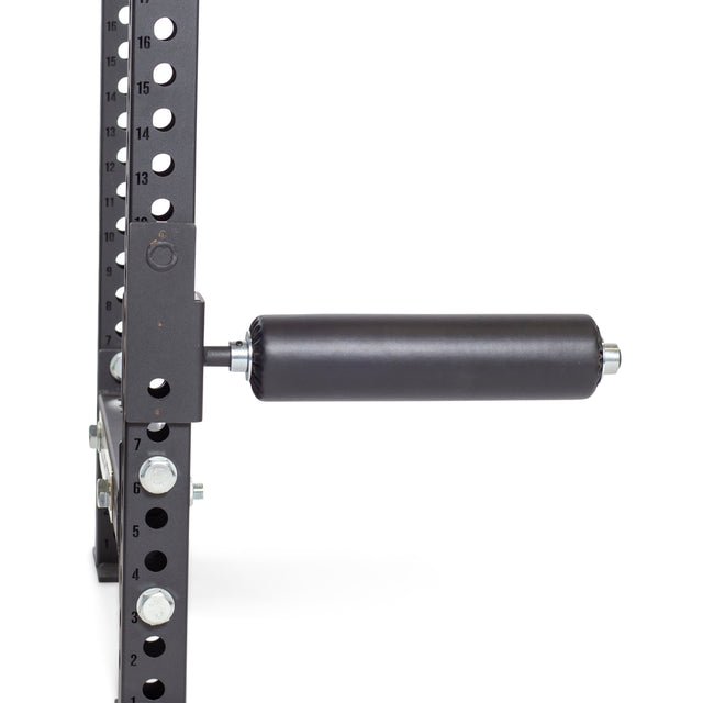 The Bells of Steel Split Squat Leg Roller Rack Attachment is a black padded cylindrical arm secured to a metal frame with numbered holes, resembling a leg roller. Essential for fitness setups, it appears against a plain white background.