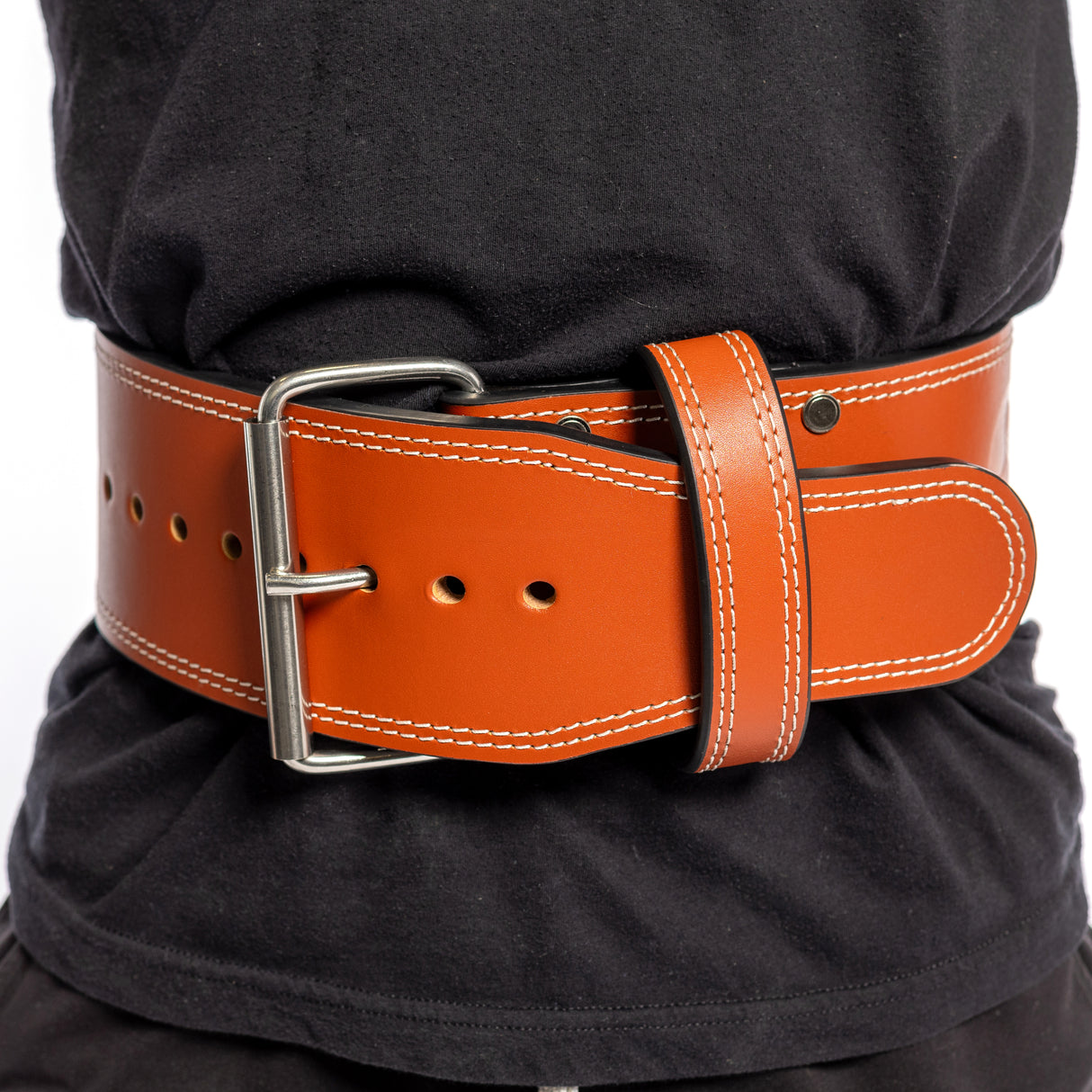 A person wears a Bells of Steel USA 10mm Leather Weightlifting Belt, featuring white stitching and a secure silver single-prong buckle, snugly fastened around their waist over a black shirt.