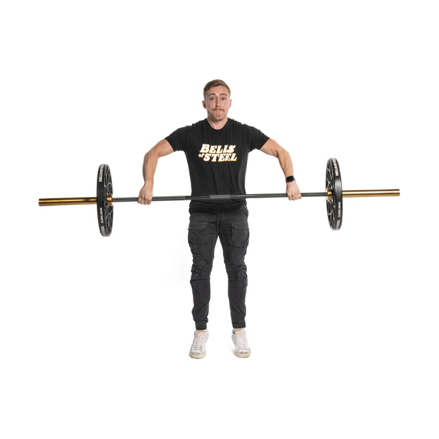 A person in a "BELLS OF STEEL" black T-shirt and pants lifts a barbell with 5 lb Technique Plates, crafted by Bells of Steel, in a gym. The virgin rubber-coated plates stand out against the plain white background.