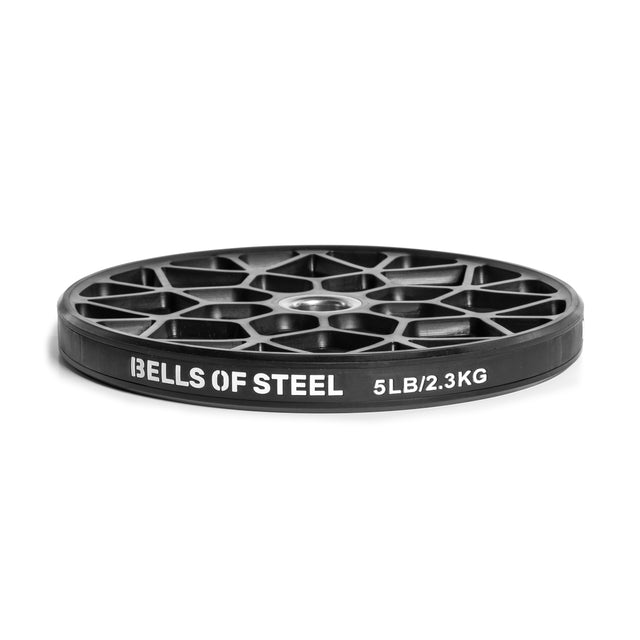 The Bells of Steel Technique Plates, weighing 5 lbs (2.3 kg) each, are black with a virgin rubber coating and feature a unique cut-out spoke design and "Bells of Steel" in white on the side.