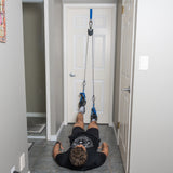 A person lies on the floor with their feet strapped into the Bells of Steel USA Rotational Pulley, using resistance bands for a leg workout or physical therapy exercise that can easily be incorporated into a bodyweight workout routine.