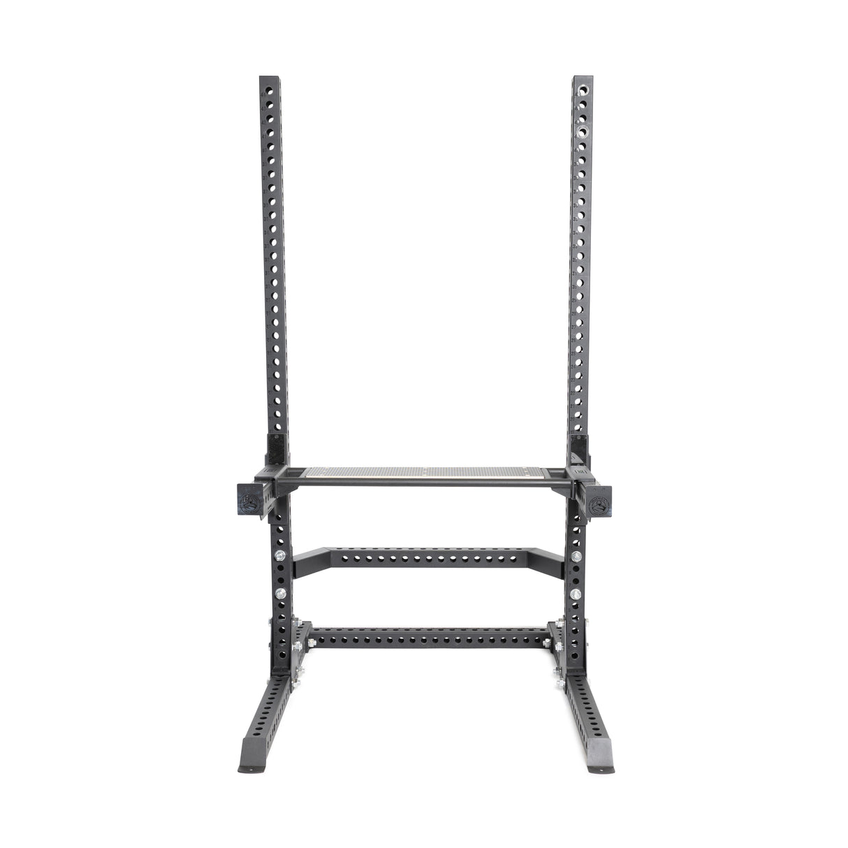 A picture of a 3"x3" black power rack features adjustable barbell holes and a rectangular base to ensure stability, complemented by the utility seat from Bells of Steel's Hydra/Manticore line for performing squats and presses in strength training.