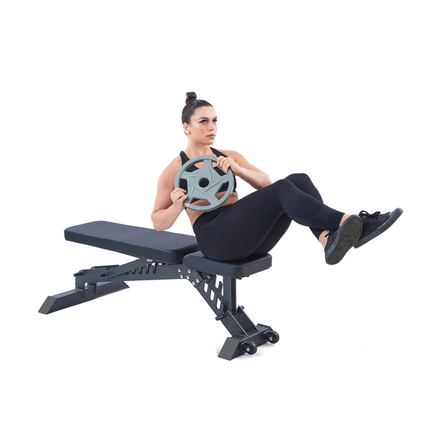 A person in black workout attire performs a core exercise on a bench, lifting legs while holding a Bells of Steel Gray Mighty Grip Olympic Weight Plate with precision grip handles for ergonomic control.