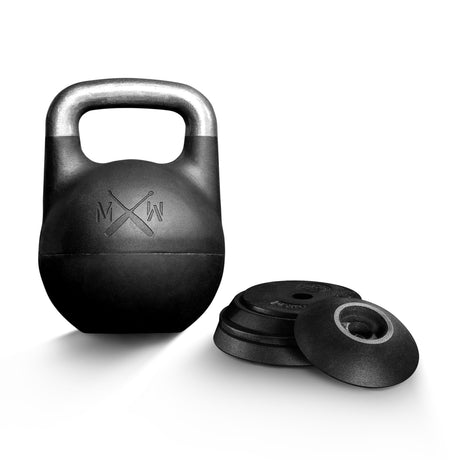 The Bells of Steel Mark Wildman Adjustable Kettlebell, featuring a metal handle and sleek black design, stands upright beside several loose weight plates on a white background.
