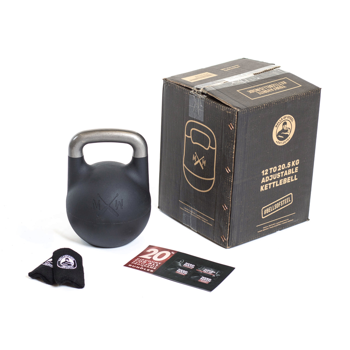 A Mark Wildman Adjustable Kettlebell by Bells of Steel is shown on a white background with a labeled cardboard box (12 to 20.5 kg). Nearby are a branded black cloth and promotional card.