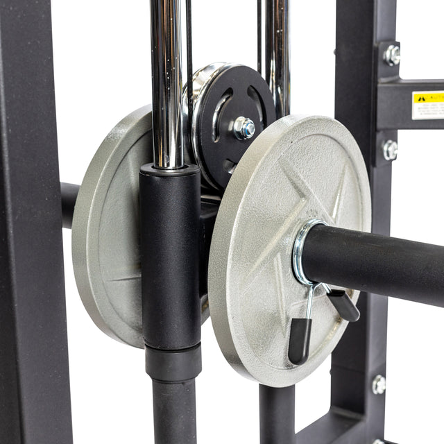 Close-up of a Functional Trainer by Bells of Steel with a silver plate, featuring metal rods, a pulley system, and black components. Cable attachments and a weight clip secure the plate in place.