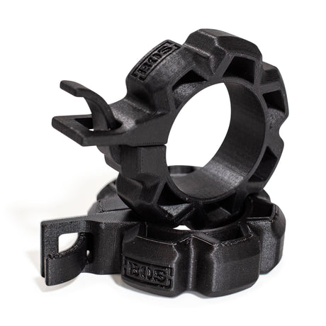 Two black, rugged Barbell Zip Clips - Half Standard (Pair) from Bells of Steel, circular with ridged edges and integrated clips, are stacked together on a white background, resembling standard barbell clips.