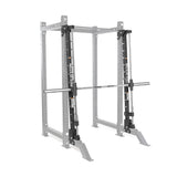 The Bells of Steel Smith Machine Rack Attachment is a silver and black metal power rack accessory with a barbell on sliding tracks, providing guided, stable weightlifting and reliable workout support.