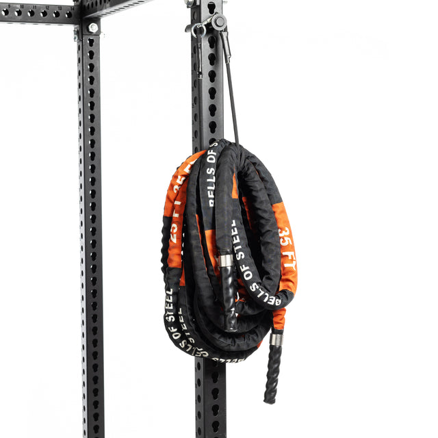 A 52.5-ft Bells of Steel battle rope with a durable sleeve hangs from a robust metal gym frame on a plain white background, ready for an intense workout.