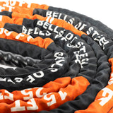 A close-up shows a coiled Battle Rope by Bells of Steel in black and orange with a durable sleeve, perfect for conditioning workouts. The spiral arrangement highlights its textured surface.