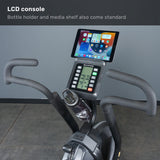 The Bells of Steel Blitz Max Air Bike offers a display console, media shelf for an iPad, bottle holder, and dual handlebars—ideal for commercial gyms—all showcased against a gray floor and wall backdrop.