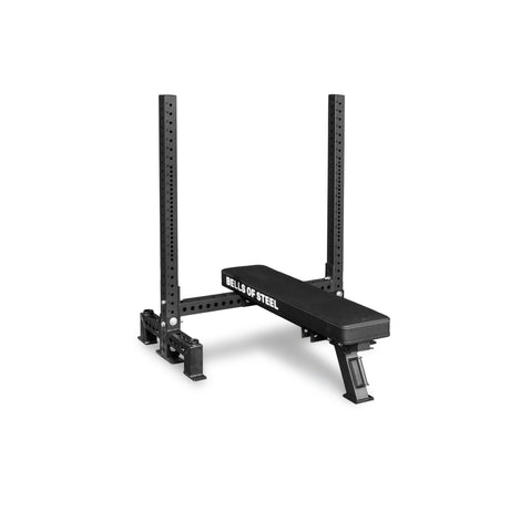 The Bells of Steel USA Two Post Converter Bench is a black bench station with side branding, an elevated padded seat, and a sturdy metal rack for barbells. Shown against a plain white background.