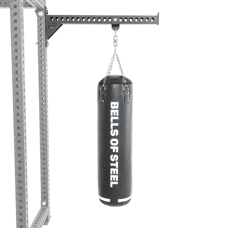 A black heavy bag from Bells of Steel USA hangs from a chain attached to a sturdy metal support frame, making this Heavy Bag Set an ideal addition to any power rack or gym setup, displayed against a white background.