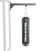 A Bells of Steel Heavy Bag Set, ideal for combat sports, hangs from a sturdy mount on a fitness rack. Its sleek design and reliability are emphasized against the plain white background.