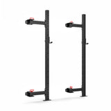 The Roc Foldable 2 Post Cage Builder by Bells of Steel features two tall black metal uprights with ⅝" holes for modular components and adjustable attachments. Each has a red pull pin and protruding hook, perfect for a home gym setup against a plain white background.