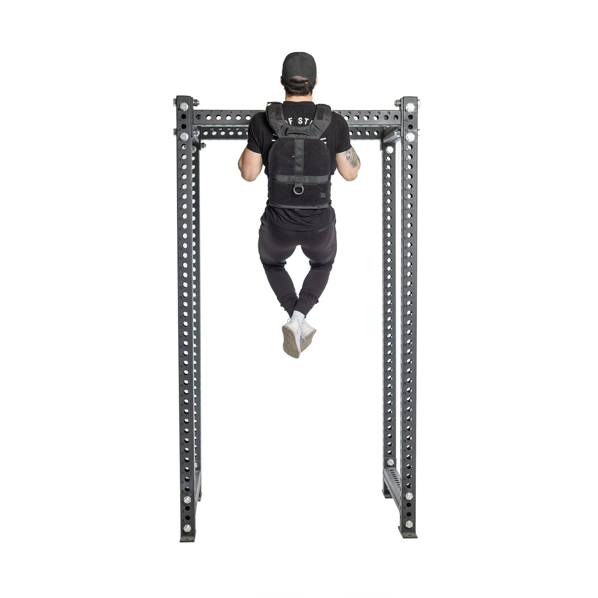 A person in a black cap and a Bells of Steel USA Weighted Vest with weight plates performs a pull-up on a sturdy metal frame, isolated against a white background.